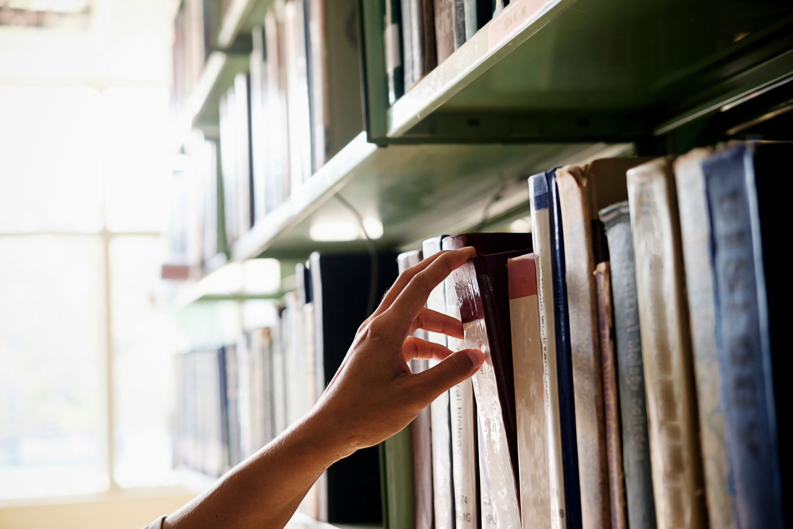 Reading concept. Asian woman selecting book from a bookshelf in
